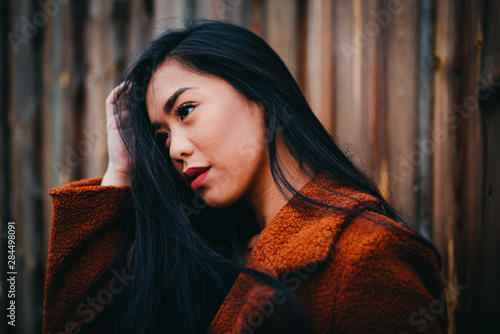 beautiful young serious asian woman with black hair and orange kashmere outdoor photo