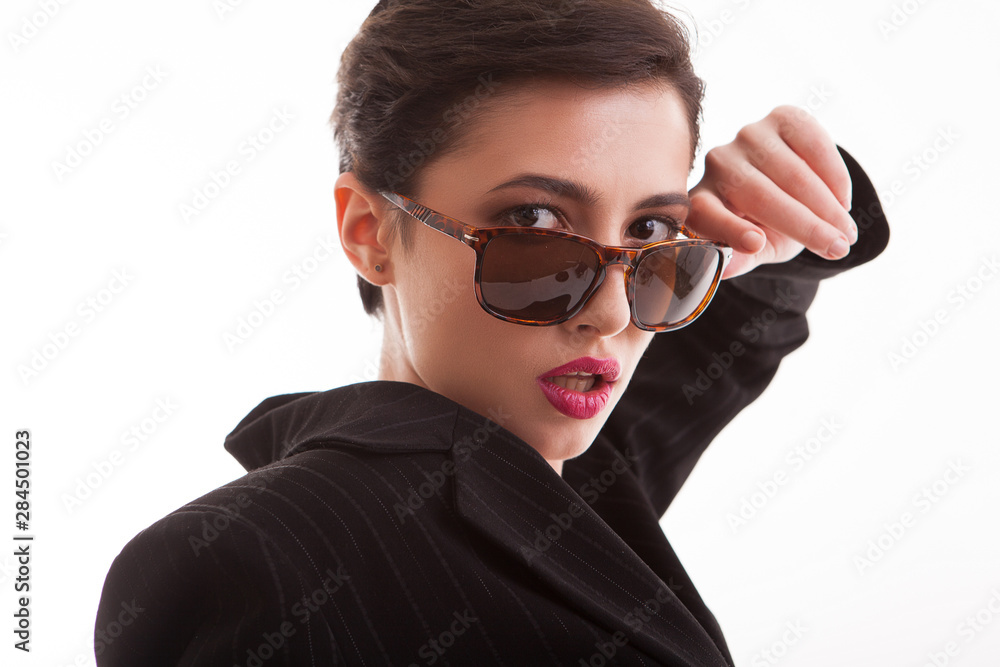 Close up portrait of beautiful yong model looking at the camera over her sunglasses over white background in studio