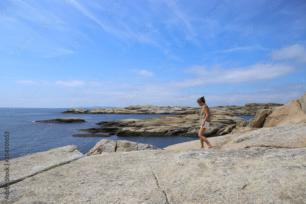 Woman admiring magestic view  of islets and rocks in The End of the Earth in Norway. Verdens Ende (World's End) is composed of various islets and rocks and is a popular recreational area with fantasti