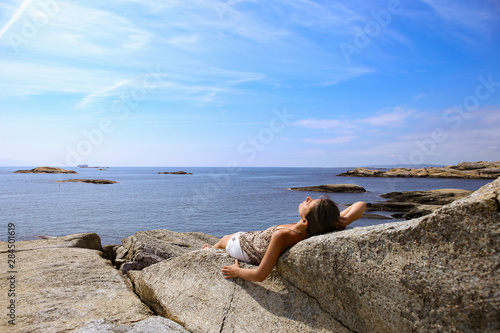 Woman sunbathing on a rock in The End of the Earth in Norway. Verdens Ende (World's End) is composed of various islets and rocks and is a popular recreational area with fantastic panoramic views. 