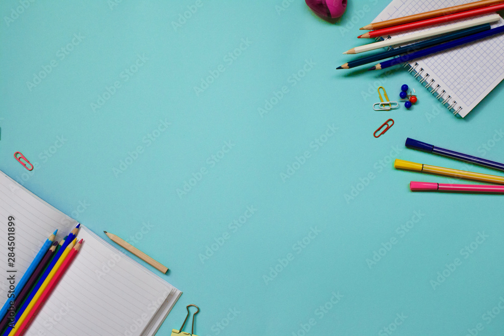 Top view school background. Flat lay back to school concept with notebook, clips, colorful pencils and school supplies on blue background. Top view school background. Flat lay back to school concept with notebook, clips, colorful pencils and school supplies on blue background.