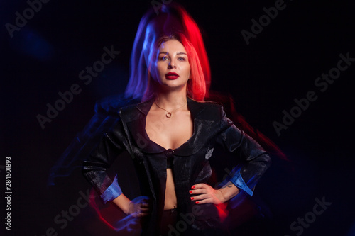 Fashion portrait of beautiful young woman wearing black jacket in studio with color filters
