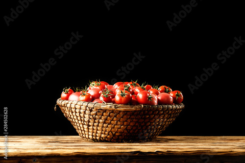 Fresh red tomatoes on wooden desk and black background 