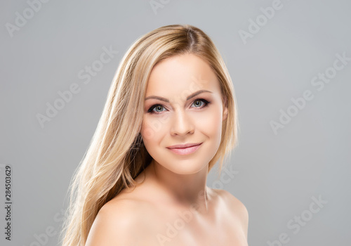 Studio portrait of young  beautiful and natural blond woman over grey background. Face lifting  plastic surgery  cosmetics and make-up concept.