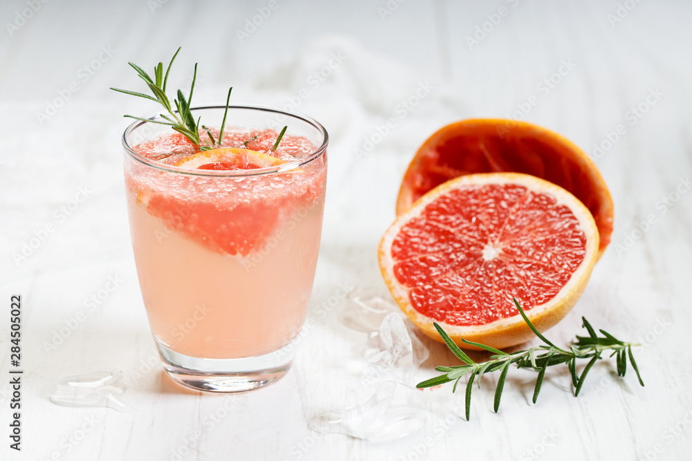 Glass of grapefruit drink with ice and rosemary Glass of grapefruit drink with ice and rosemary