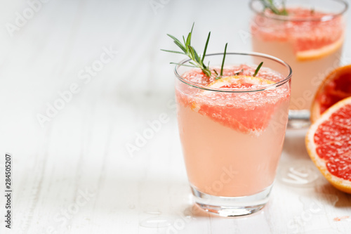 Glass of grapefruit drink with ice and rosemary