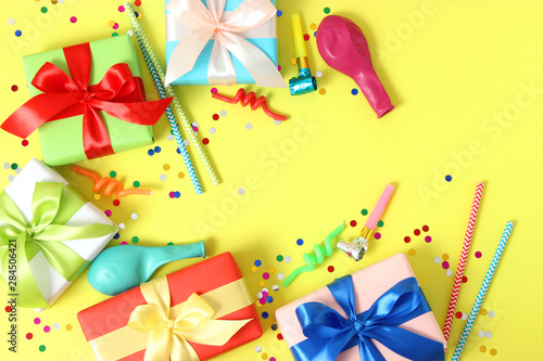 gifts, confetti and party accessories on a colored background top view.