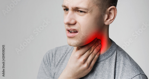 Young man suffering from tonsillitis, pulping his neck photo