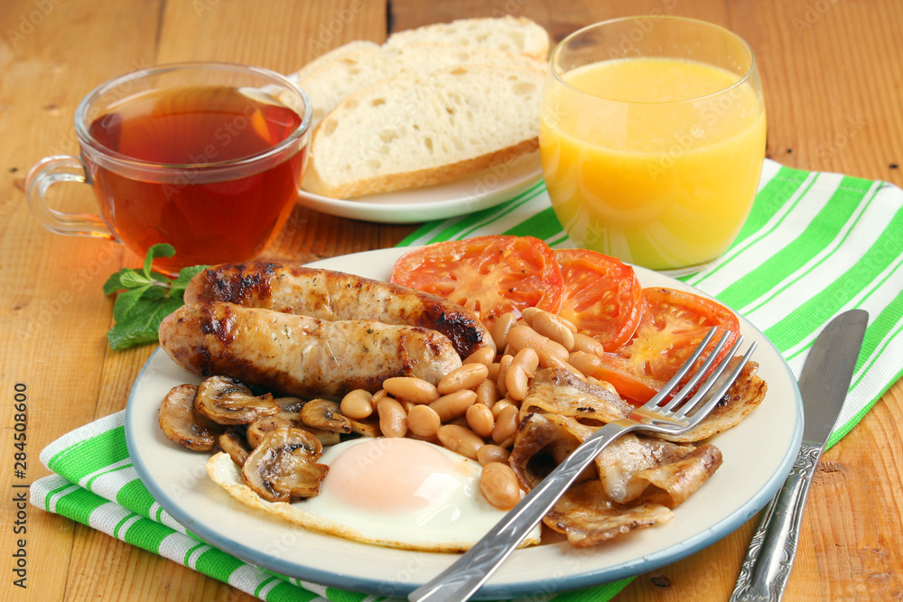 Classic English breakfast served: eggs, bacon, beans, juice and tea	v