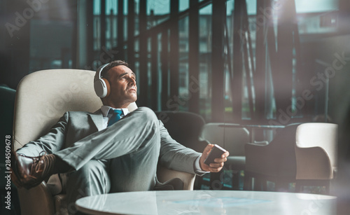 Change your vision. Businessman is listening to podcast via headphones. Copy space on the right side