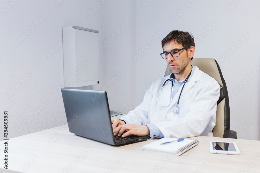 young doctor man working on laptop at the consult. Modern Medical concept indoors young doctor man working on laptop at the consult. Modern Medical concept indoors