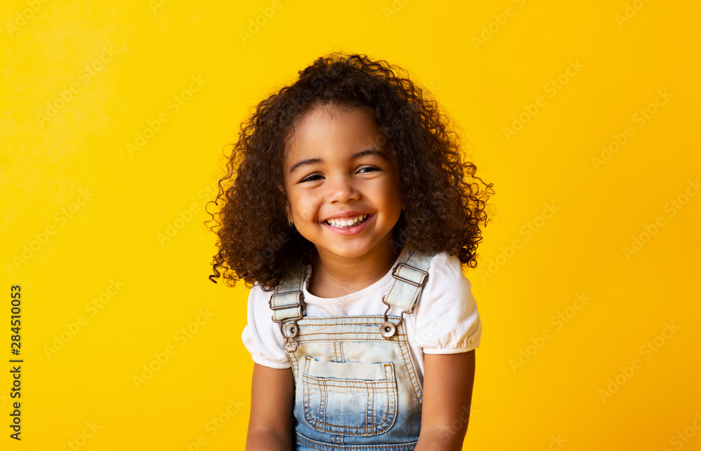 Happy smiling african-american child girl, yellow background - obrazy, fototapety, plakaty 
