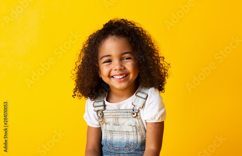 Happy smiling african-american child girl, yellow background © Prostock-studio