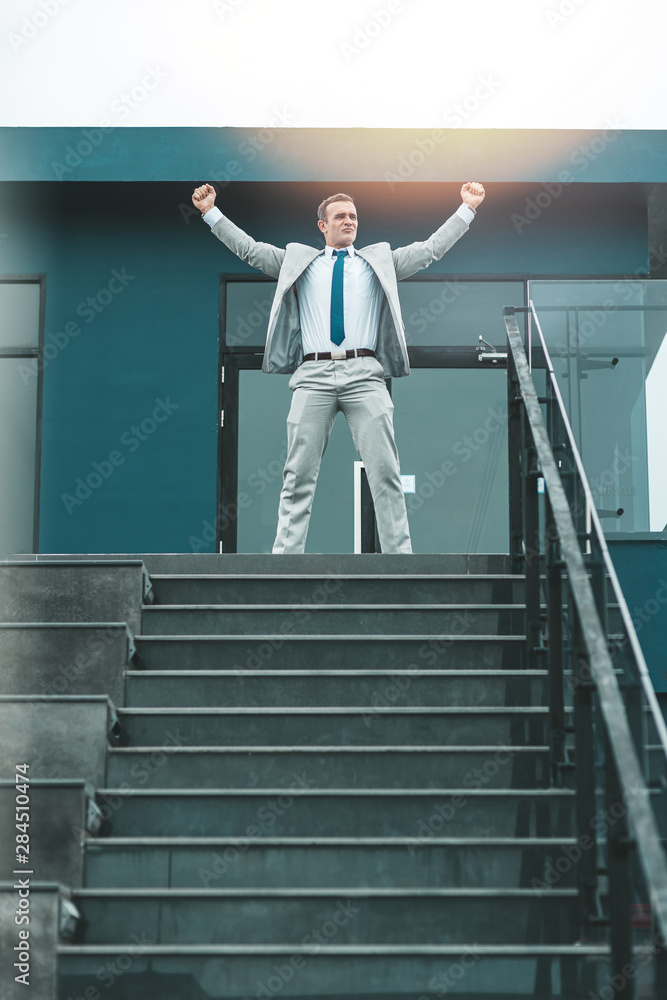 Time of glory. Businessman left the office with his arms raised high in victory. Copy space in lower part