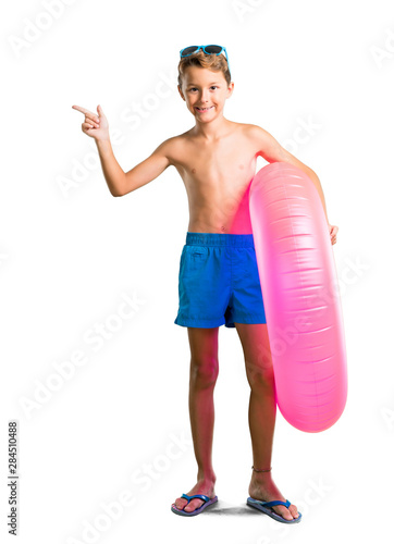 A full-length shot of Child on summer vacation pointing finger to the side and presenting a product on isolated white background