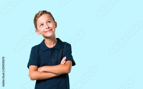 Little boy stand and looking up on blue background