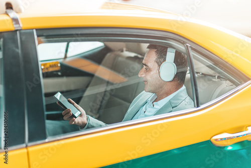 Be comfortable. Businessman with headphones rides in a taxi.