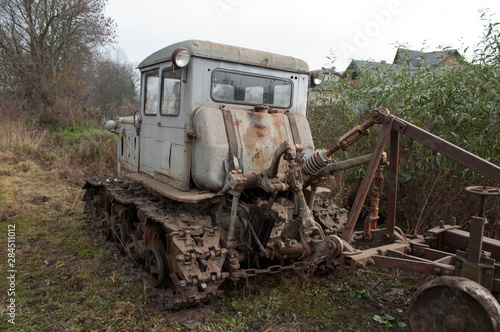 Vintage grey broken bulldozer. Abandoned old rusty crawler tractor near the field