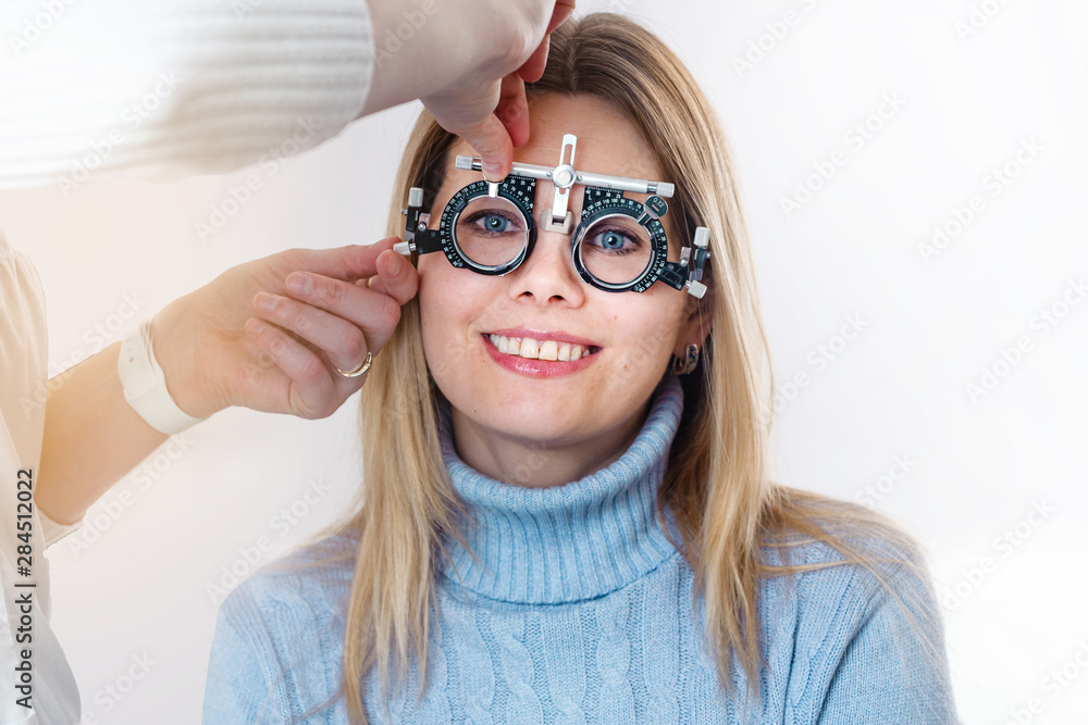 Ophthalmologist picks up glasses for a woman with a set of trial eyeglass lenses Ophthalmologist picks up glasses for a woman with a set of trial eyeglass lenses