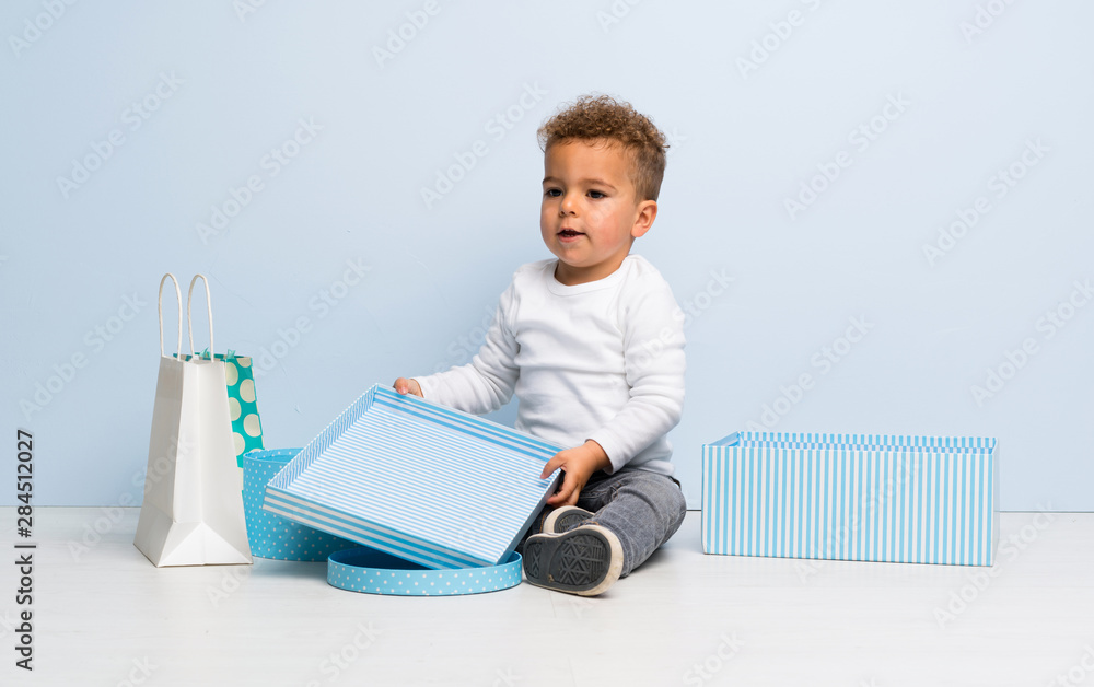 kid over isolated blue background with gifts and bags kid over isolated blue background with gifts and bags