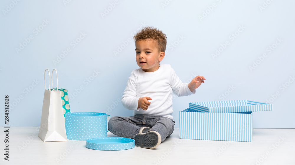 kid over isolated blue background with gifts and bags kid over isolated blue background with gifts and bags