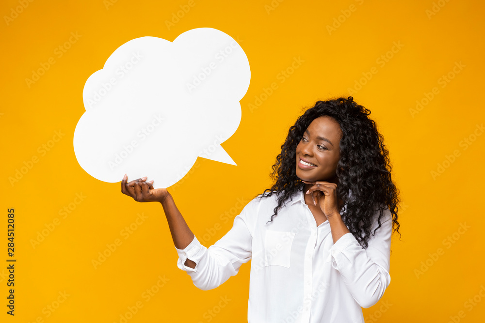Playful afro girl looking at communication bubble in her hand - obrazy, fototapety, plakaty 