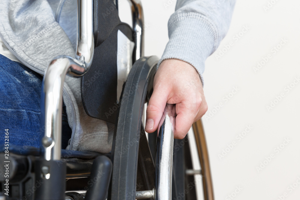 Detail of disabled woman holding a hand on wheel of a wheelchair. Detail of disabled woman holding a hand on wheel of a wheelchair.