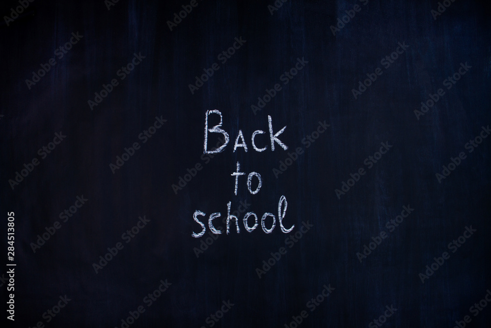 Obraz premium White chalk handwritten inscription of back to school in center of blackboard background. Preparing pupils children students for study at university, college, academy. Autumn mood concept.
