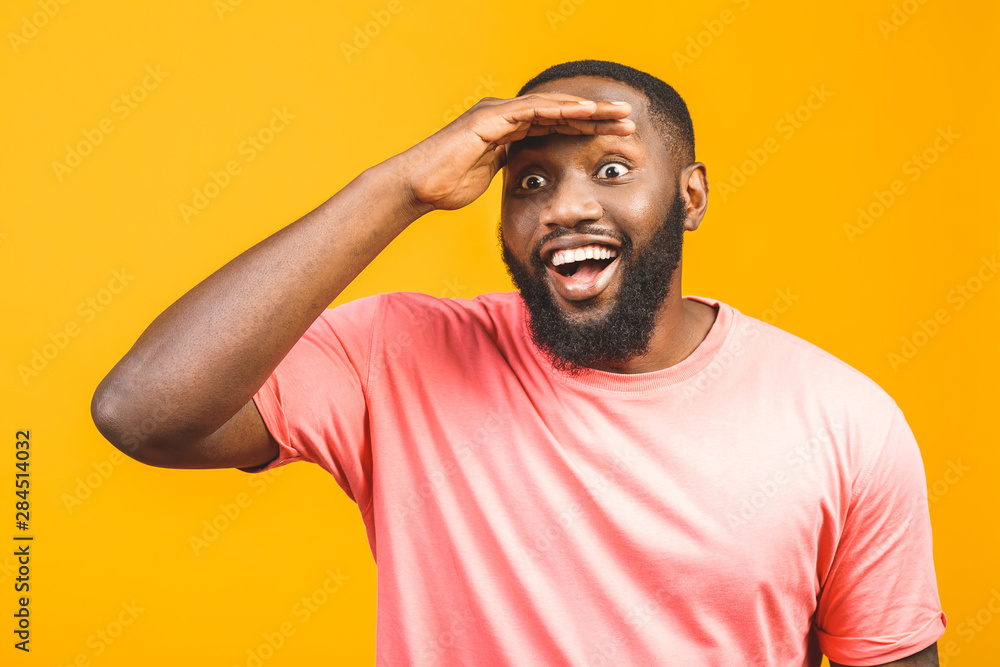 Portrait of a cheerful young african man standing against yellow background. Portrait of a cheerful young african man standing against yellow background.