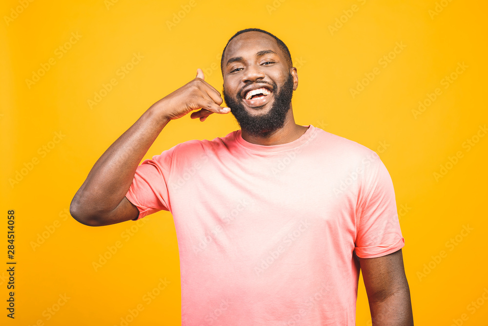 Portrait of a cheerful young african man standing against yellow background. - obrazy, fototapety, plakaty 