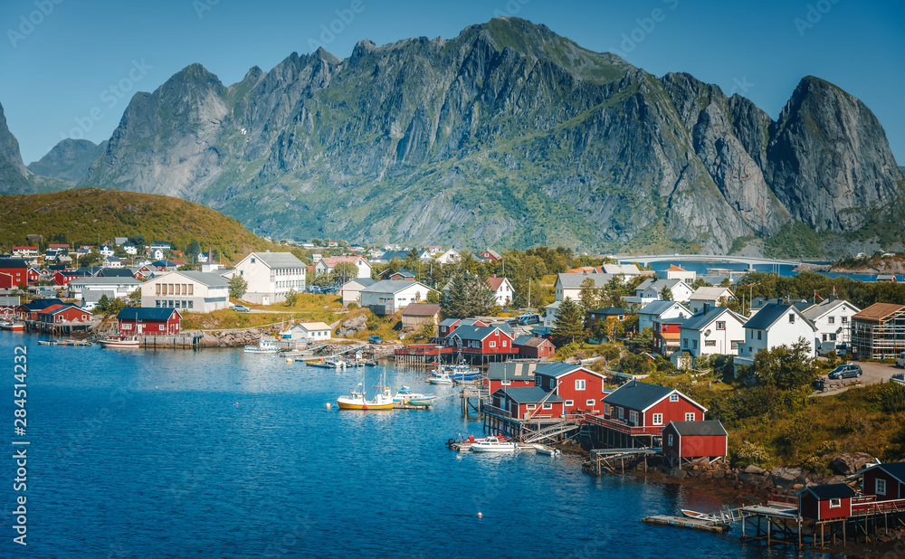 View of the city of Reine on the Lofoten islands, a beautiful bright landscape, white and red houses on a background of rocks at sunset