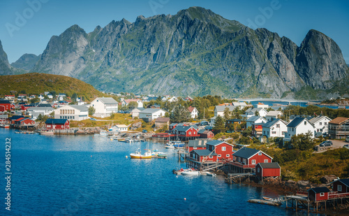 View of the city of Reine on the Lofoten islands, a beautiful bright landscape, white and red houses on a background of rocks at sunset