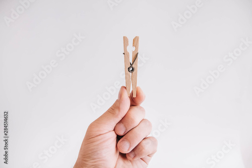 Male hand holding wooden clothespin on white background photo