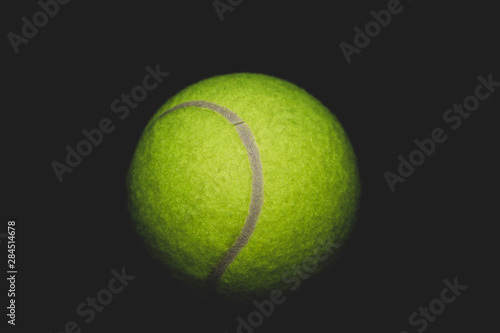 Green tennis ball isolated on black. sport equipment