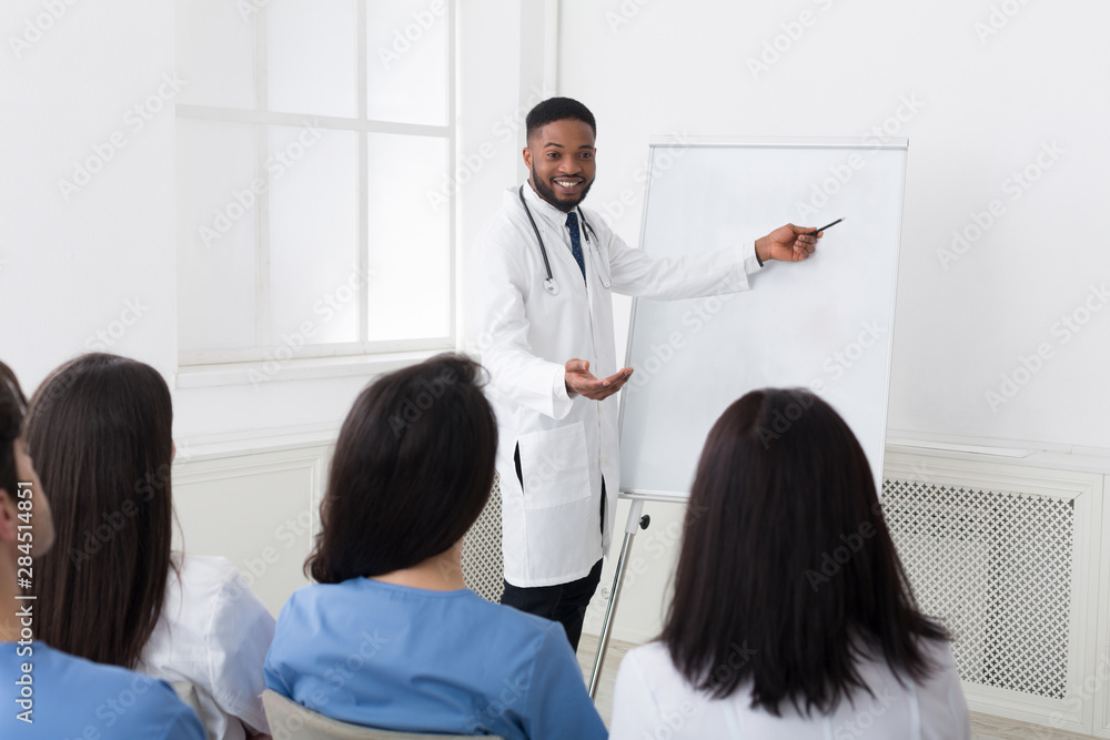 Obraz premium African-american cardiologist giving information to interns at seminar