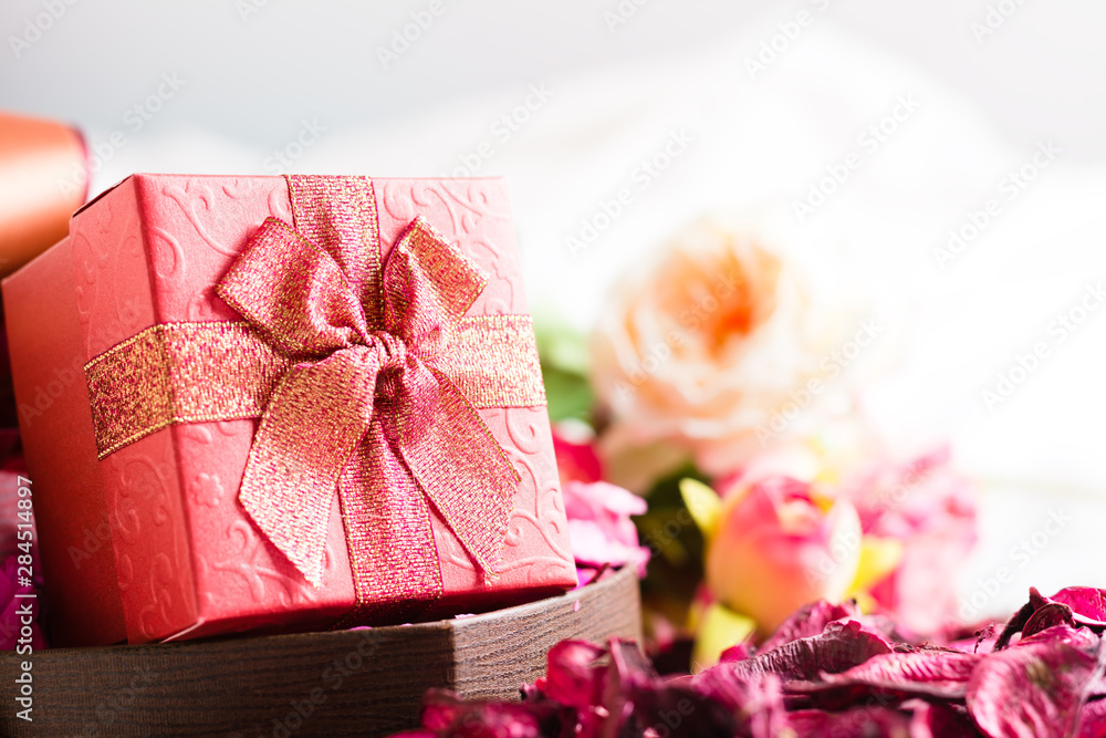 Beautiful red gift box with blurred background of roses Beautiful red gift box with blurred background of roses
