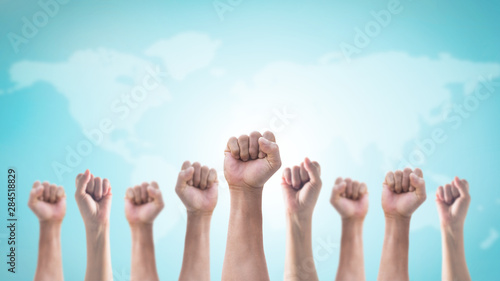 International human rights or labor day with Hands with clenched fist of people crowd (men and women) isolated on world map and sky background photo