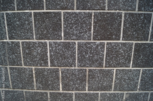 The wall is made of masonry. Gray bricks on a facade wall.