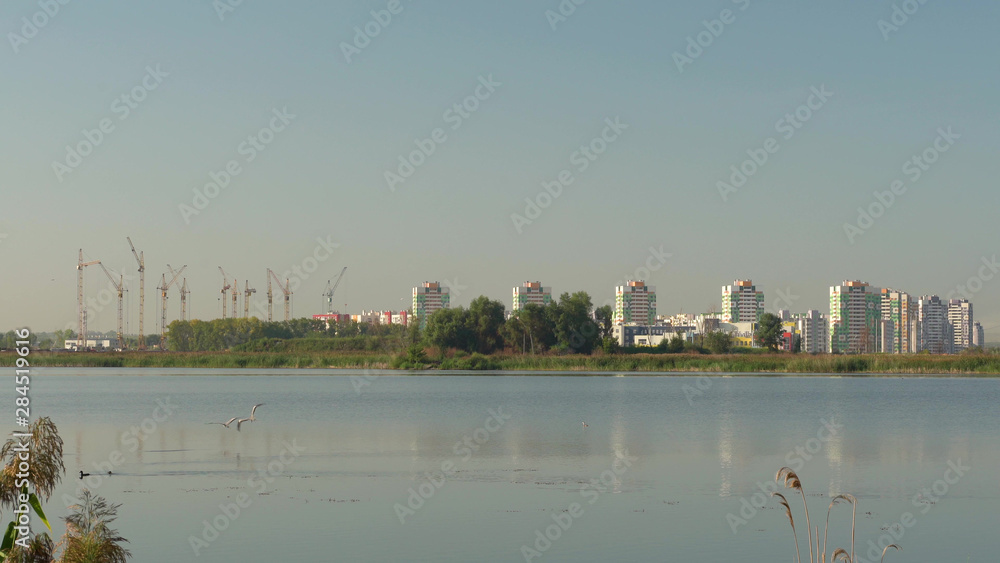 Obraz premium Building crane and buildings under construction against evening sky,