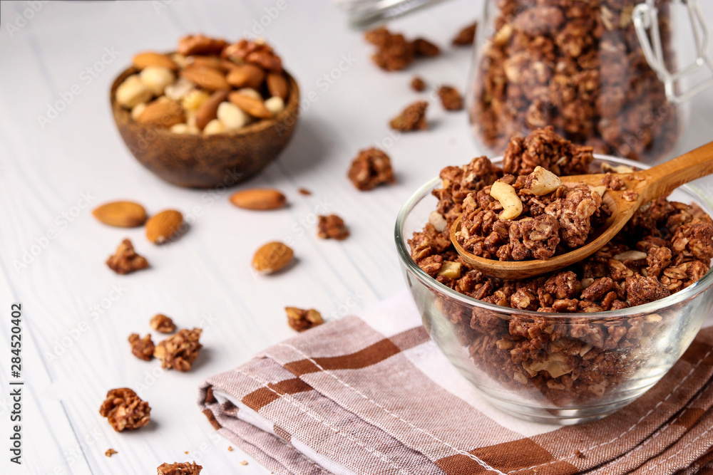 Granola crispy muesli with natural honey, chocolate and nuts in a glass bowl against a white background, healthy food, horizontal orientation