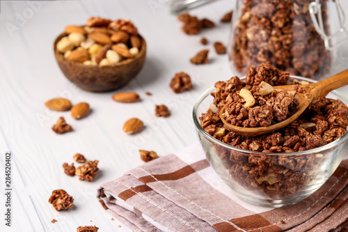 Granola crispy muesli with natural honey, chocolate and nuts in a glass bowl against a white background, healthy food, horizontal orientation
