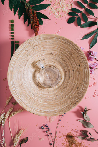 Creative flat lay top view of bamboo bowl with perfume on pastel millennial pink paper background copy space. Template for text lettering blogging