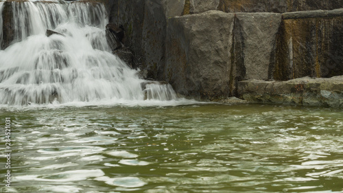 Small waterfall flows into a pond. rushing stream water