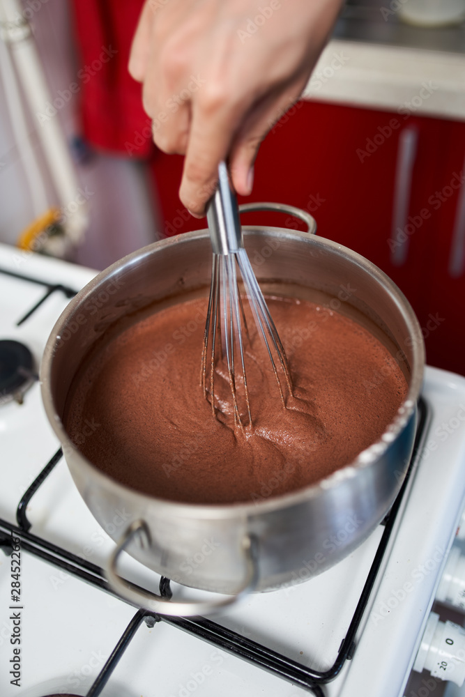 Fototapeta premium Preparing homemade chocolate pudding, closeup on hands