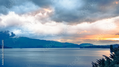 Fototapeta Naklejka Na Ścianę i Meble -  Sunset over the lake and the tops of the mountains. Overcast