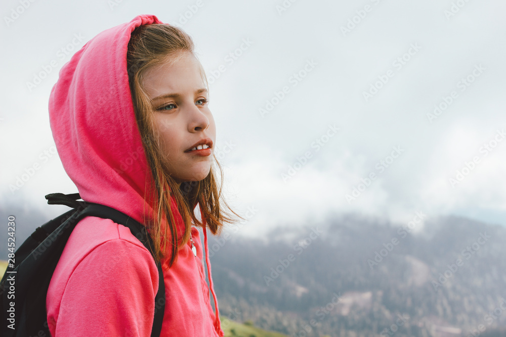 Tween girl with backpack looking on beautiful mountains in clouds, family travel concept Tween girl with backpack looking on beautiful mountains in clouds, family travel concept