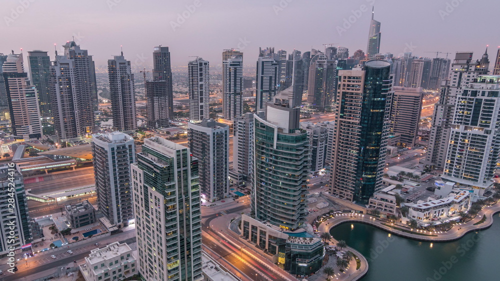 Fototapeta Aerial top view of Dubai Marina night to day timelapse. Modern towers and traffic on the road