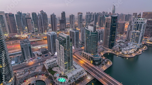 Aerial top view of Dubai Marina night to day timelapse. Modern towers and traffic on the road