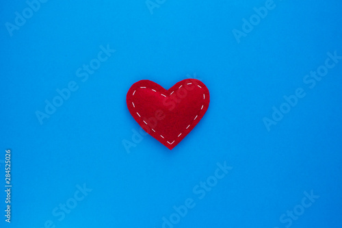 Red heart fabric with white threads on a blue background Love, romance concept. Felt bright hearts with embroidered lines.