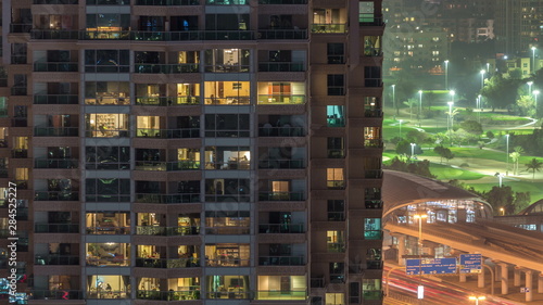 Lights in windows of modern multiple story building in urban setting at night timelapse
